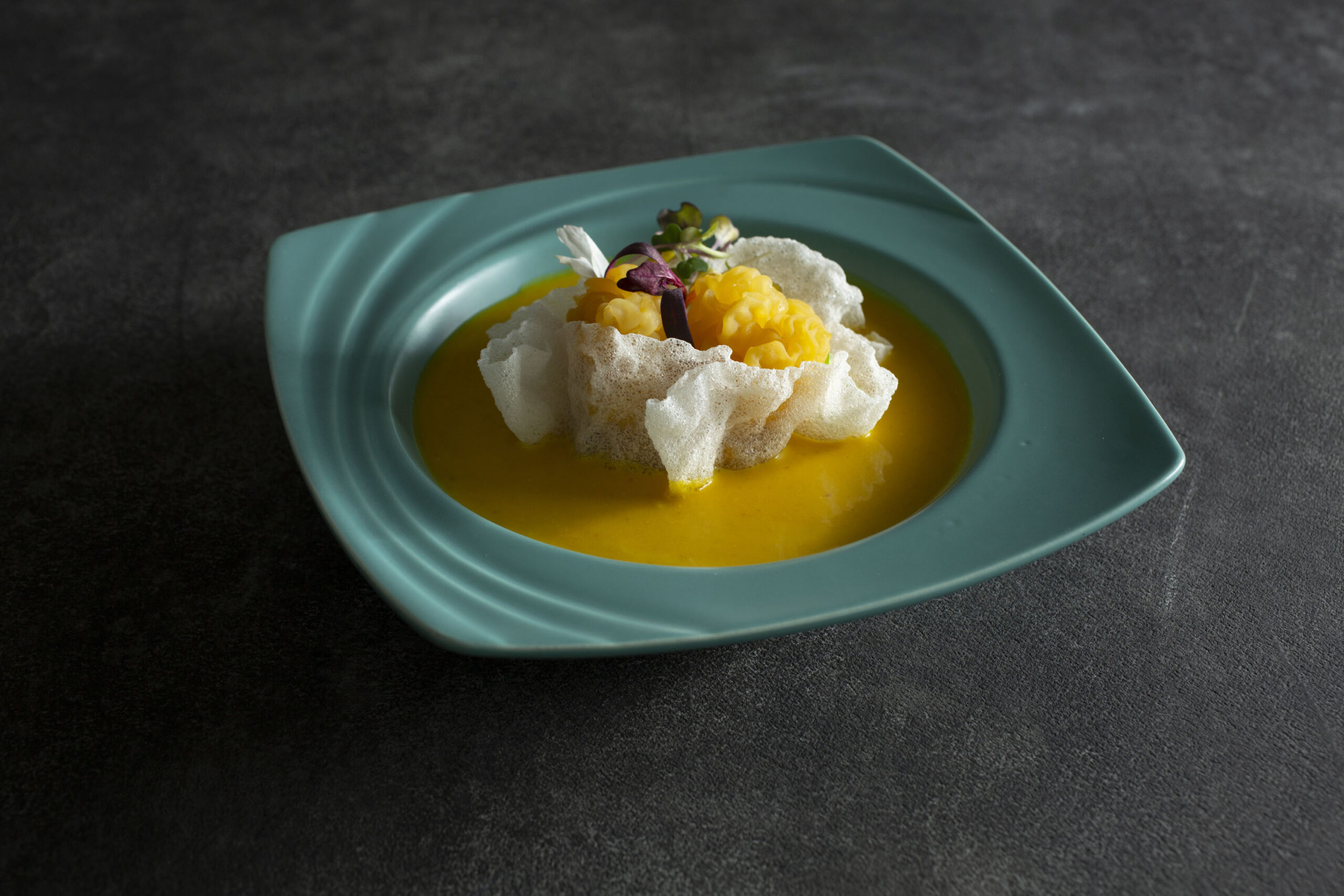 A tasting-menu dish on a turquoise plate at Taste of Beauty