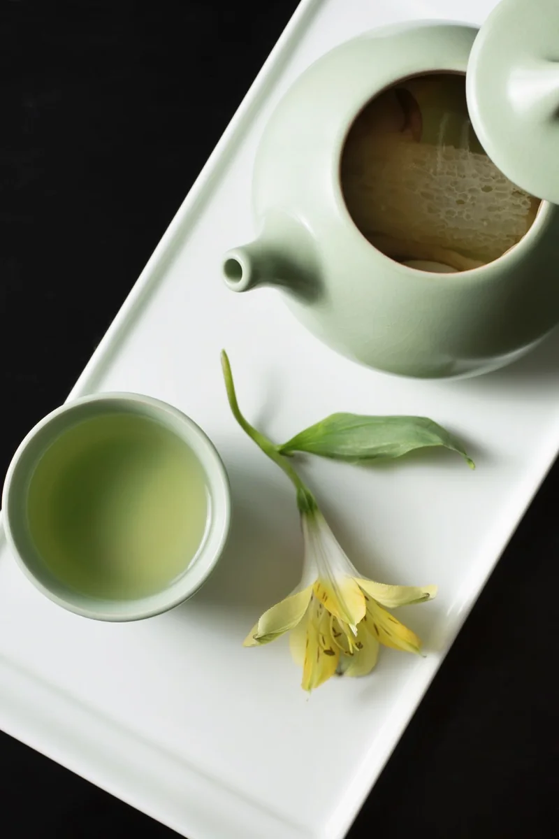 Mushroom broth poured from a pale green teapot into a matching cup