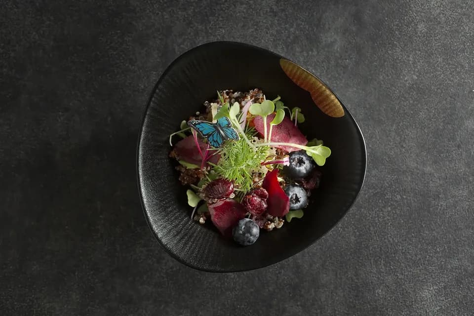 Quinoa, beets, berries and microgreens in a dark bowl