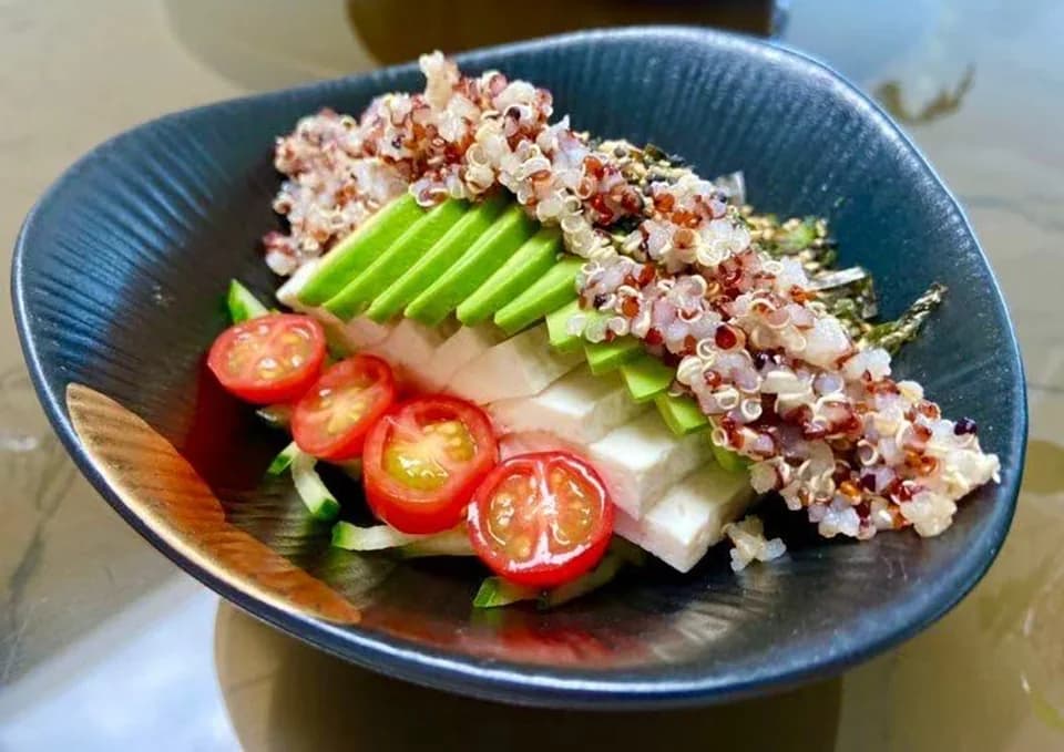 Quinoa, tofu, sliced avocado and cherry tomatoes in a blue bowl