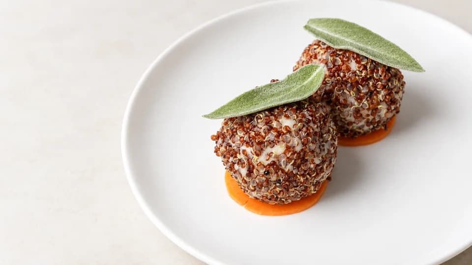 Two quinoa-coated spheres topped with fresh perilla leaves